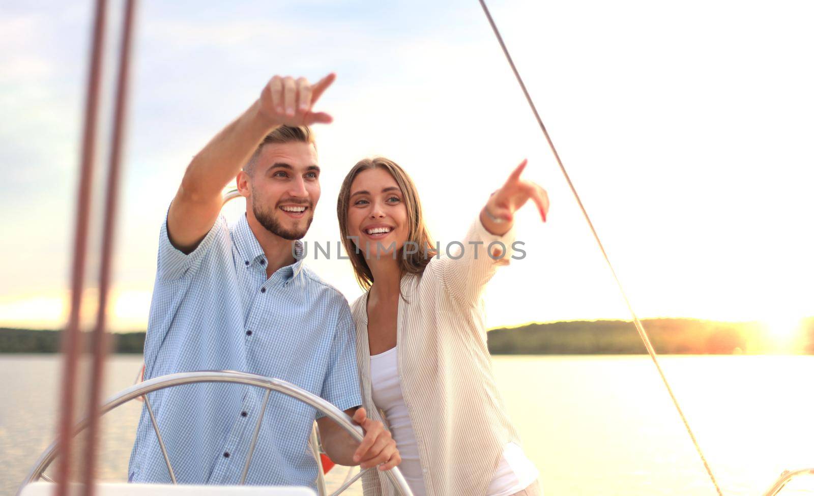 beautiful young couple looking away while standing together on yacht.