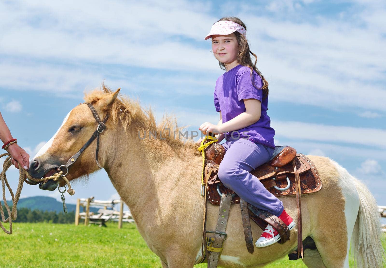 happy child ride farm animal brown pony with blue sky in background and beautiful nature