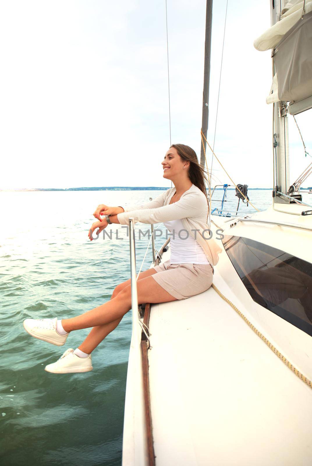 Relaxing attractive young woman on vacation sitting on yacht.