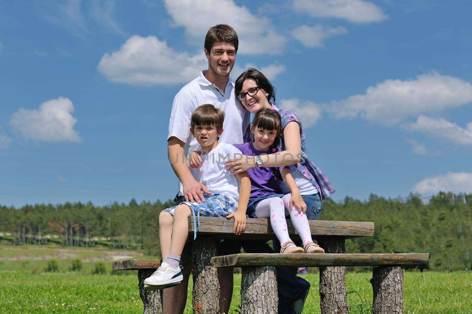 happy young family with their kids have fun and relax outdoors in nature with blue sky in background