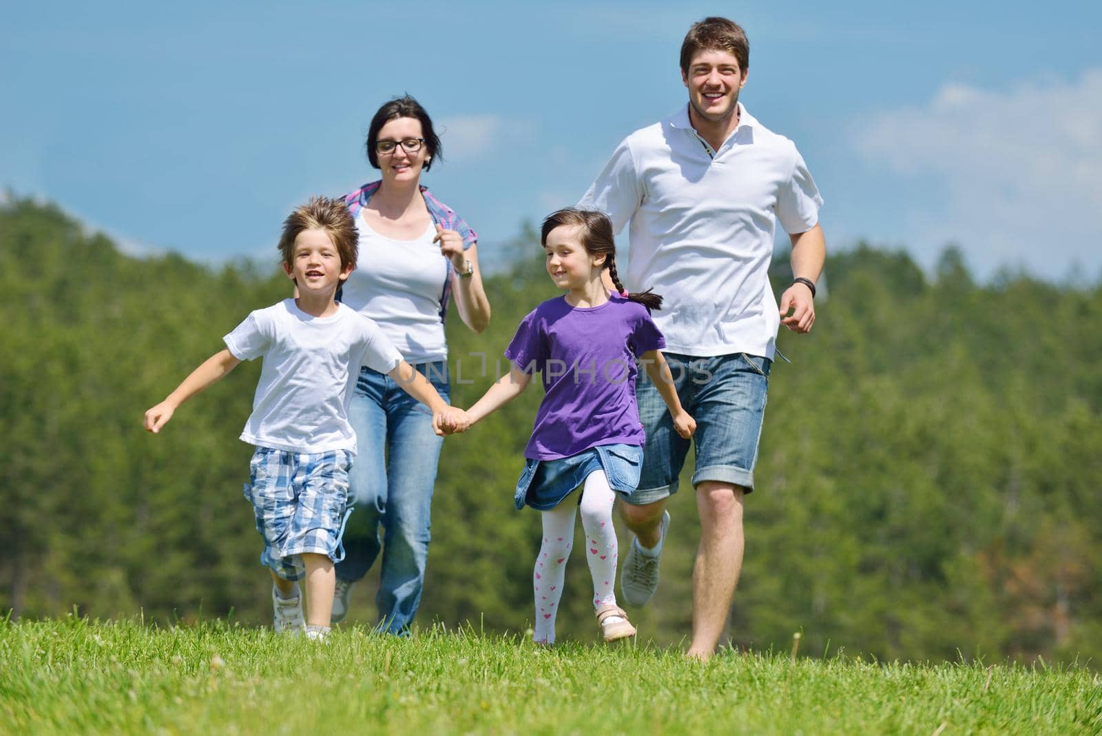 happy young family with their kids have fun and relax outdoors in nature with blue sky in background