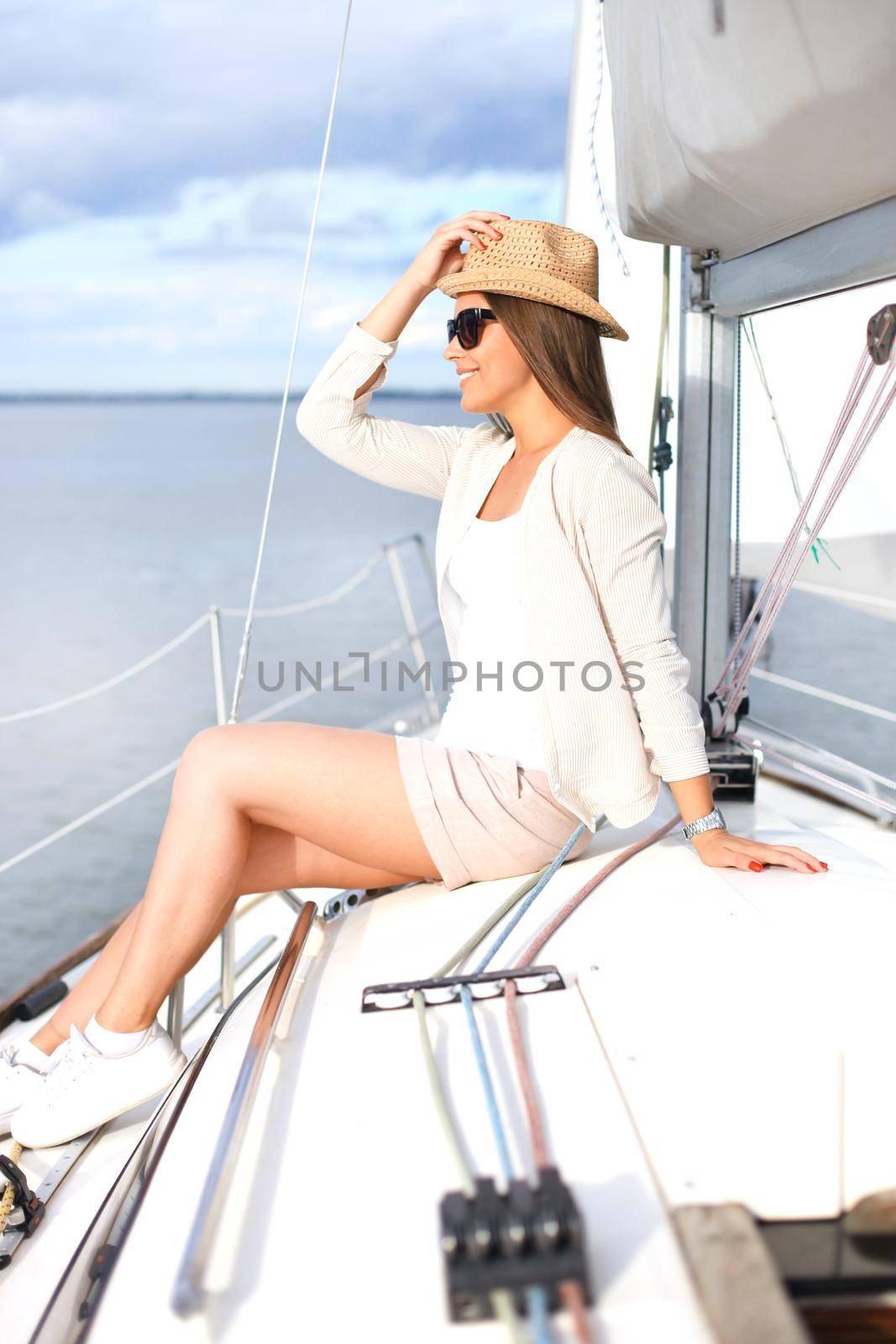 Relaxing attractive young woman on vacation sitting on yacht.