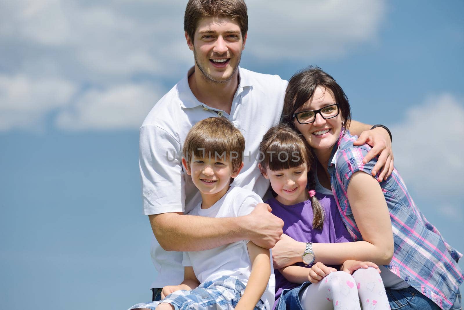 happy young family with their kids have fun and relax outdoors in nature with blue sky in background