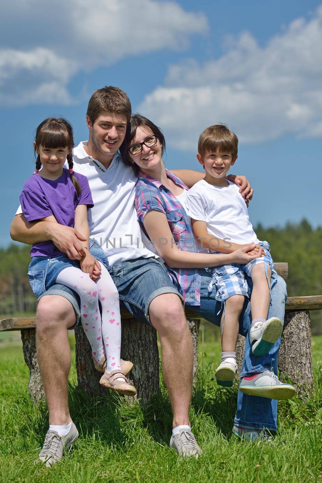 happy young family with their kids have fun and relax outdoors in nature with blue sky in background