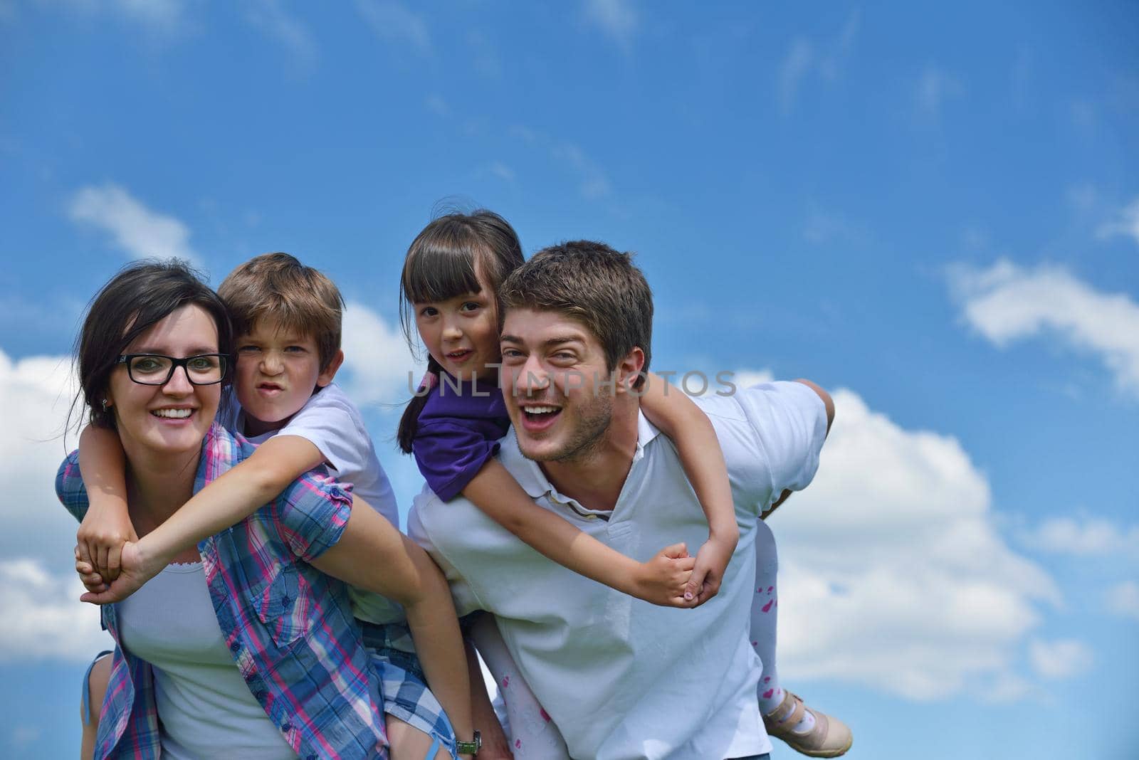 happy young family with their kids have fun and relax outdoors in nature with blue sky in background