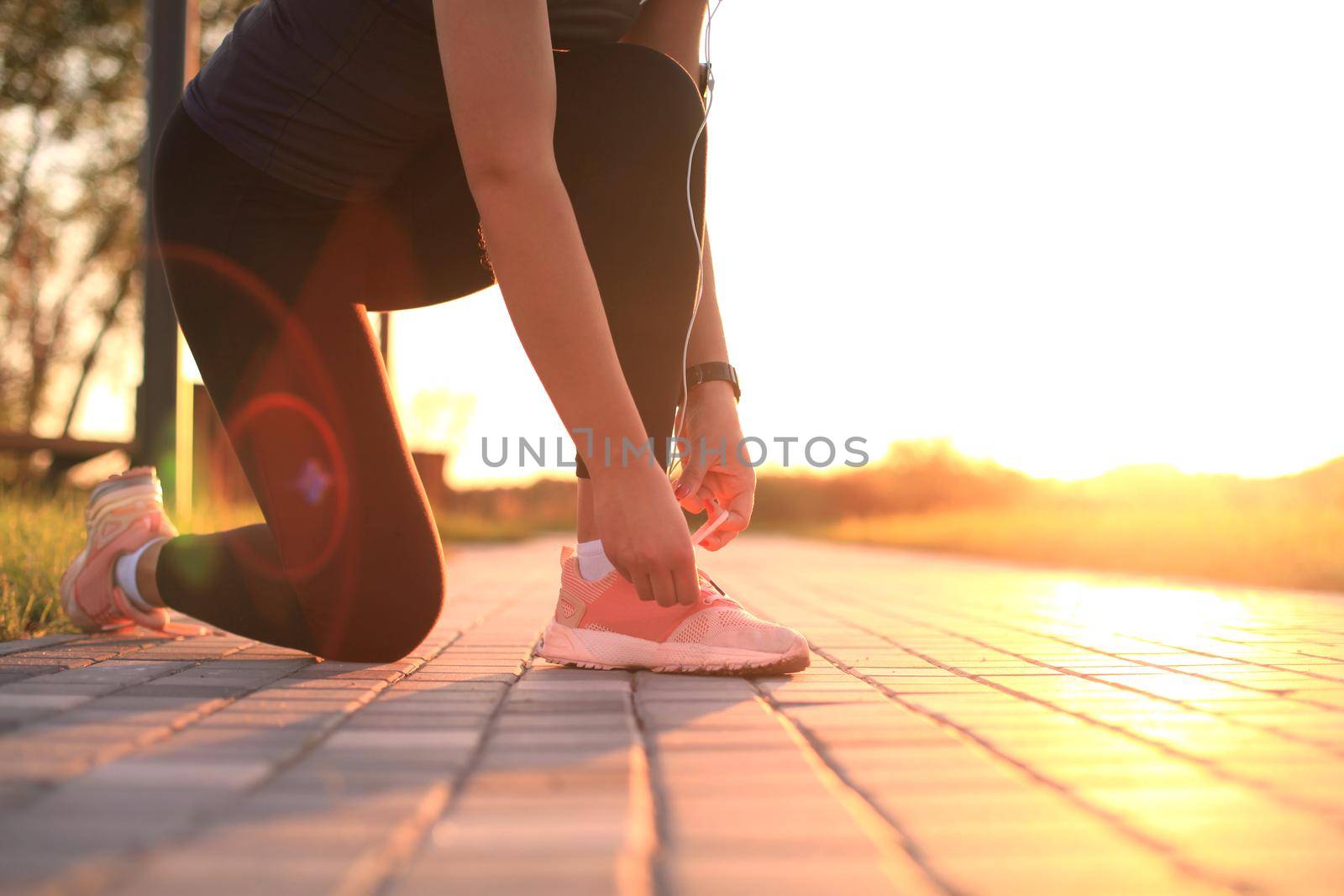 Young fitness attractive sporty girl runner ties up the shoelaces on her sports shoes getting ready to run