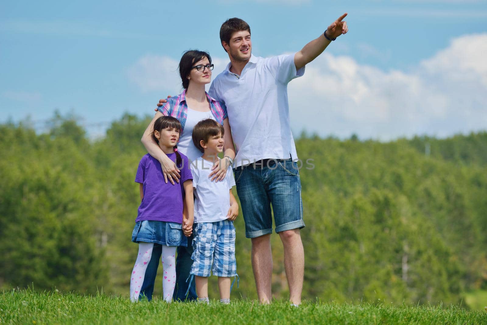 happy young family with their kids have fun and relax outdoors in nature with blue sky in background