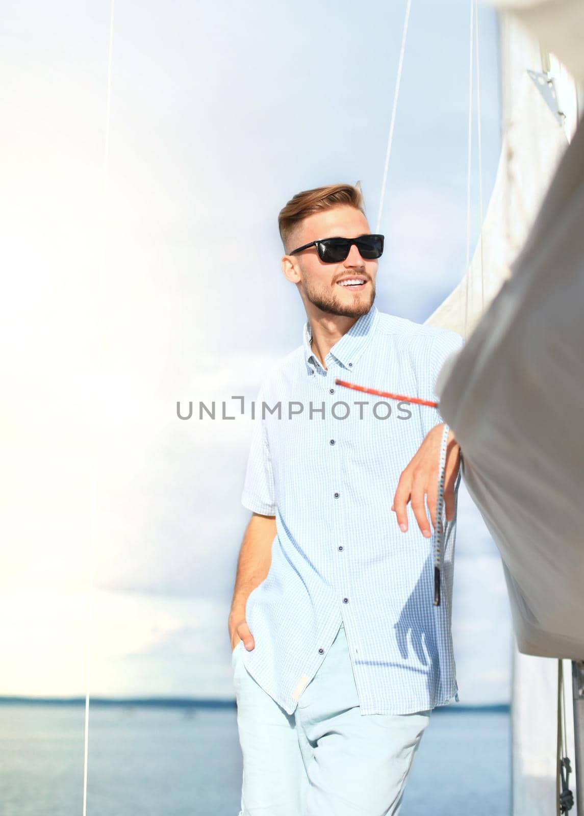 Relaxing man happily on the vacation sailboat yacht standing on a deck.