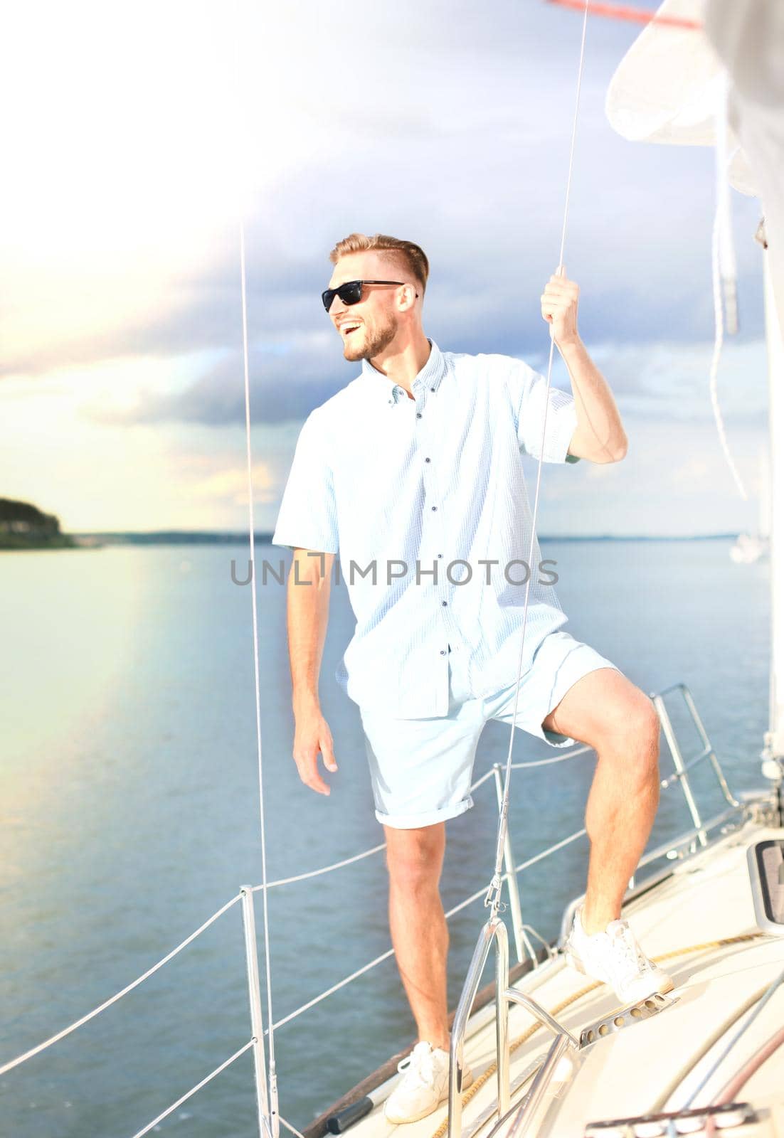 Relaxing man happily on the vacation sailboat yacht standing on a deck. by tsyhun