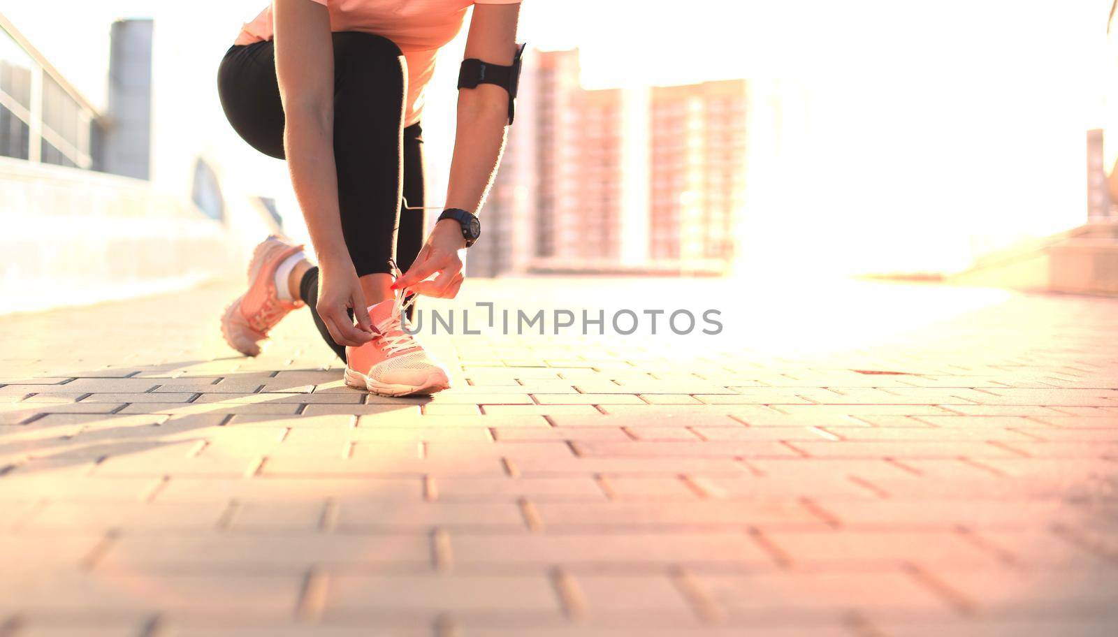 Young fitness attractive sporty girl runner ties up the shoelaces on her sports shoes getting ready to run