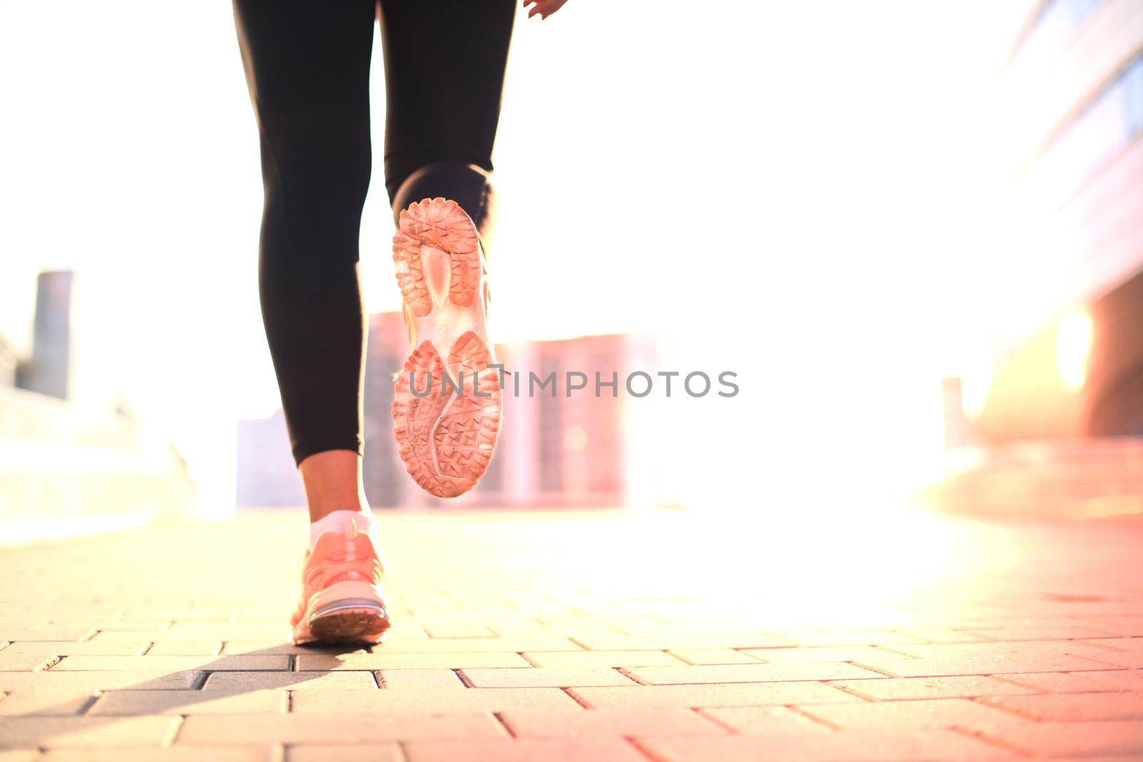 Runner feet running on road closeup on shoe, outdoor at sunset or sunrise in city