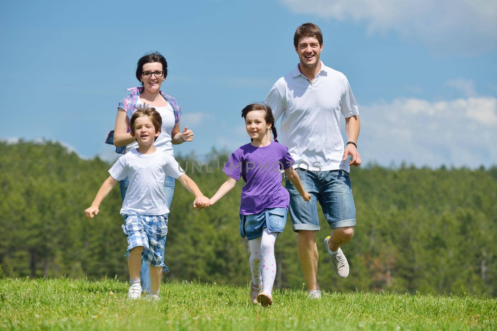 happy young family with their kids have fun and relax outdoors in nature with blue sky in background