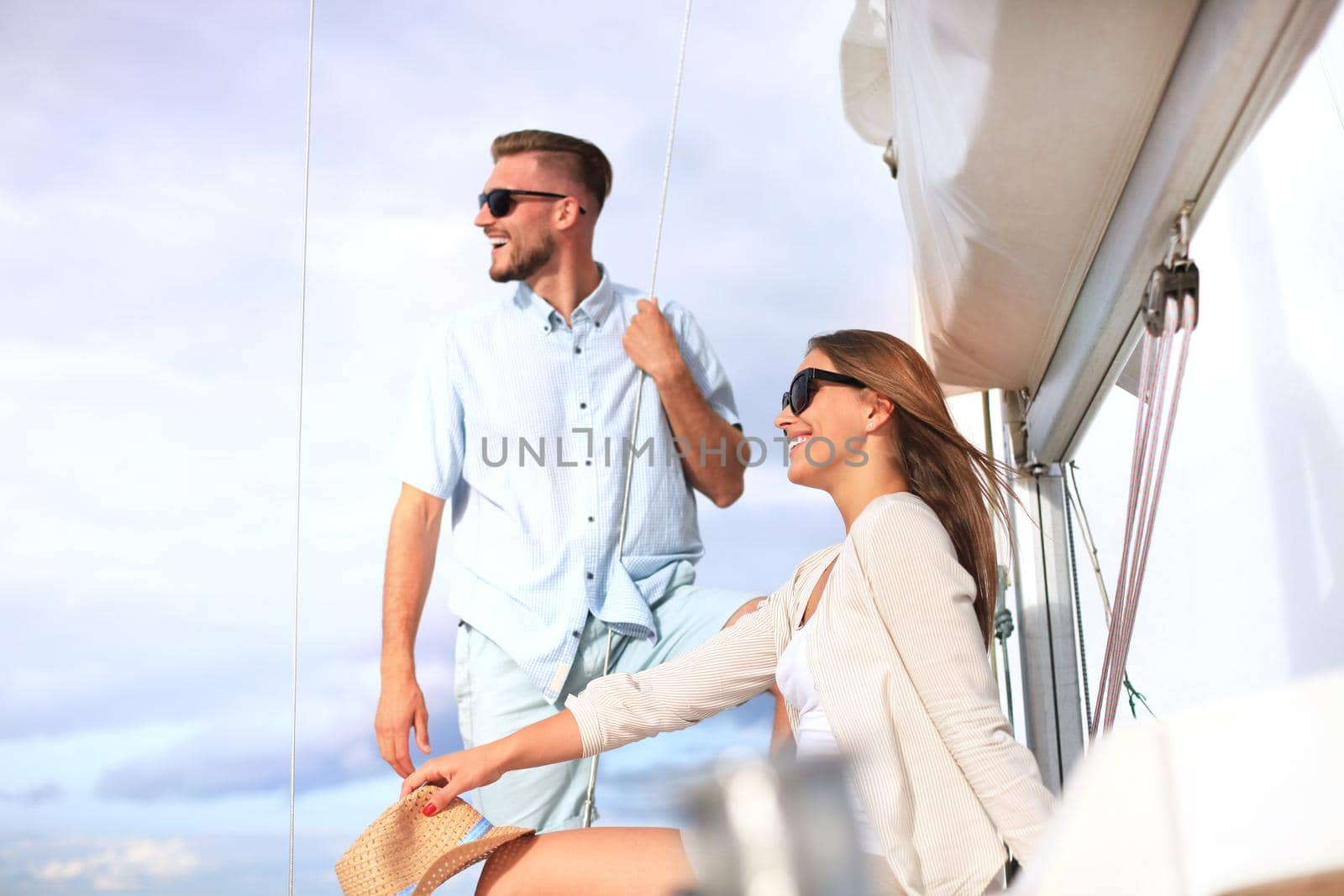 Attractive couple on a yacht enjoy bright sunny day on vacation.