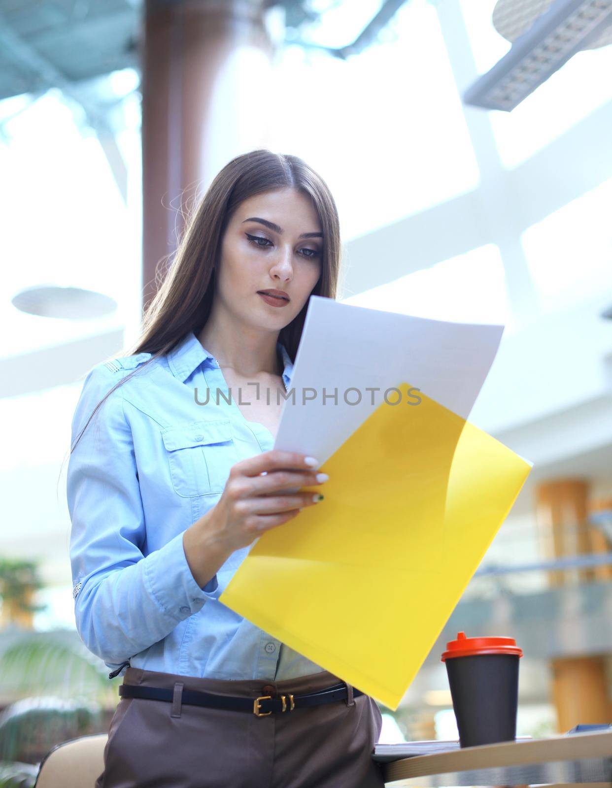 Concentrated business lady comparing documents at office.