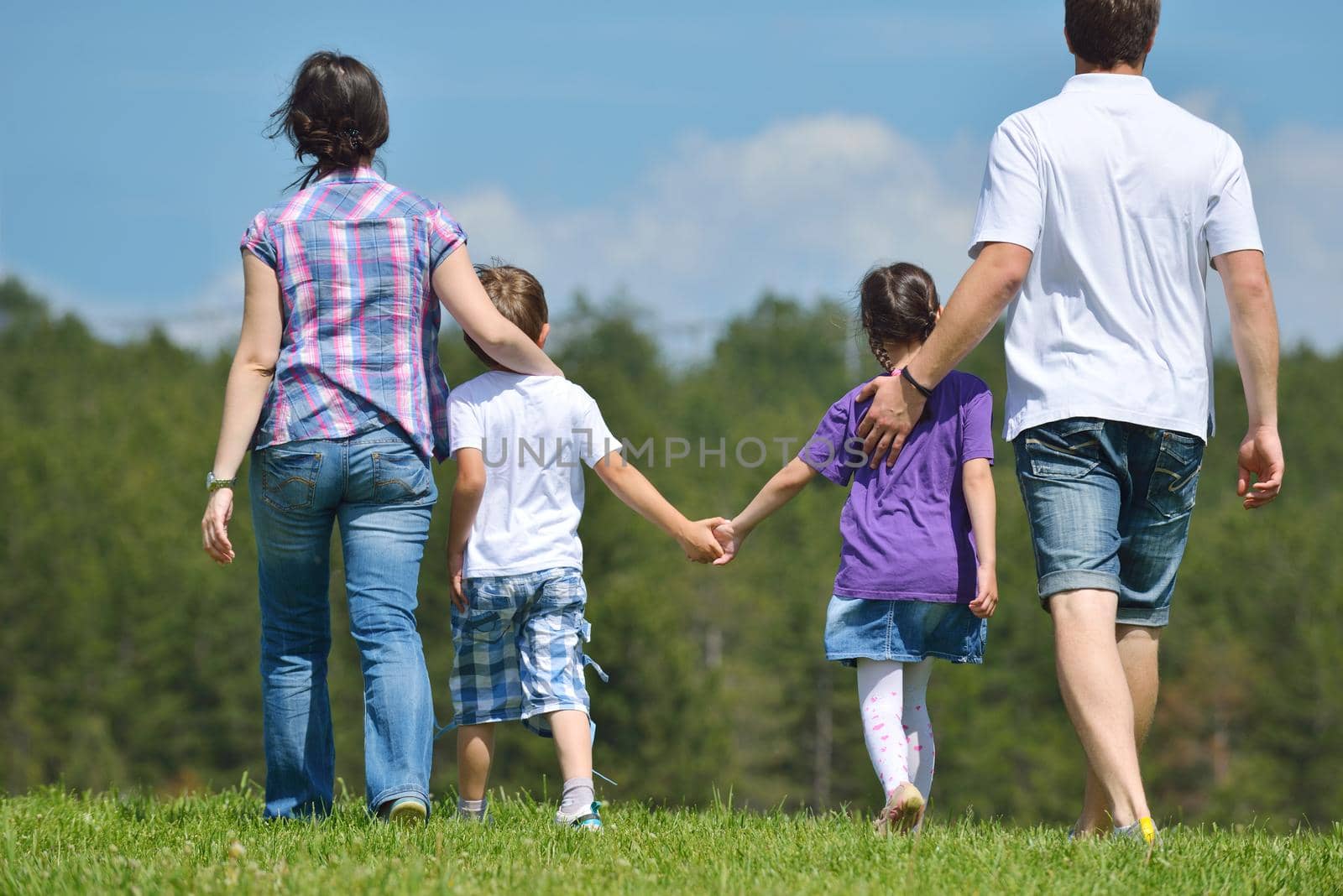 happy young family with their kids have fun and relax outdoors in nature with blue sky in background