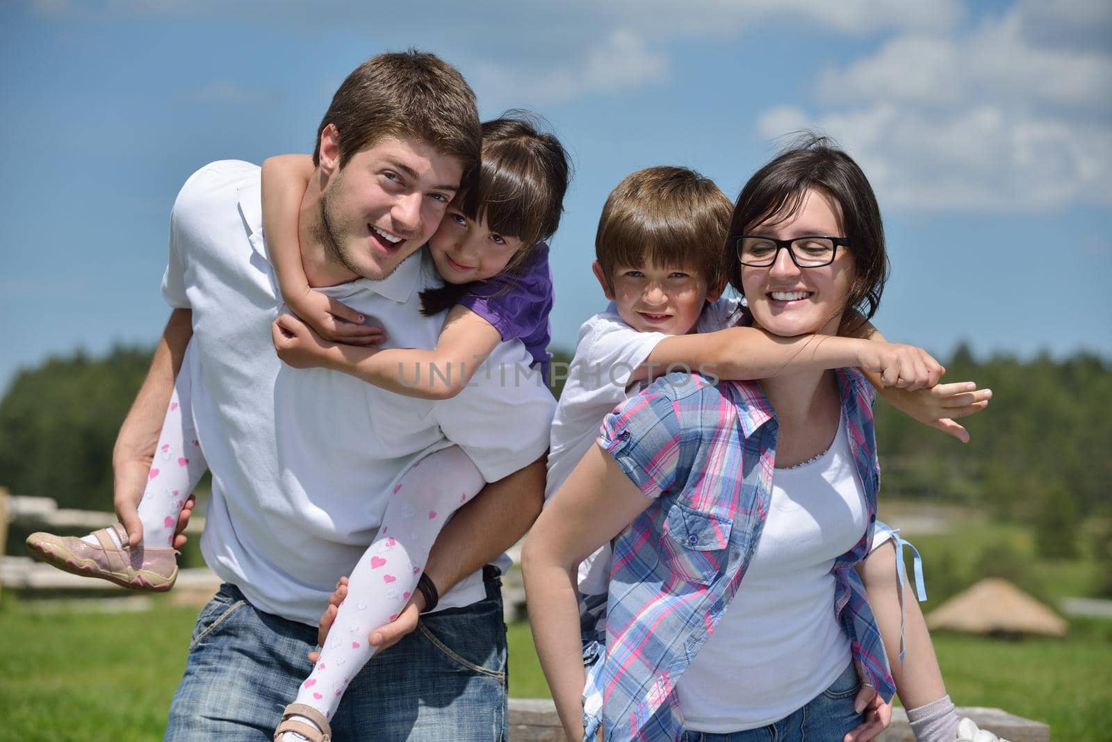 happy young family with their kids have fun and relax outdoors in nature with blue sky in background