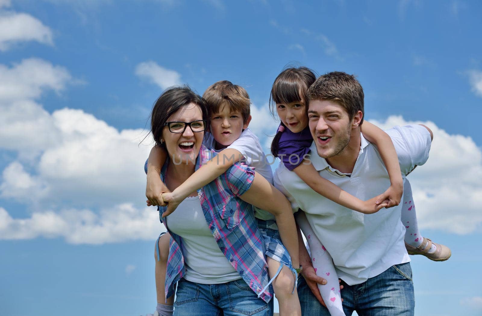 happy young family with their kids have fun and relax outdoors in nature with blue sky in background