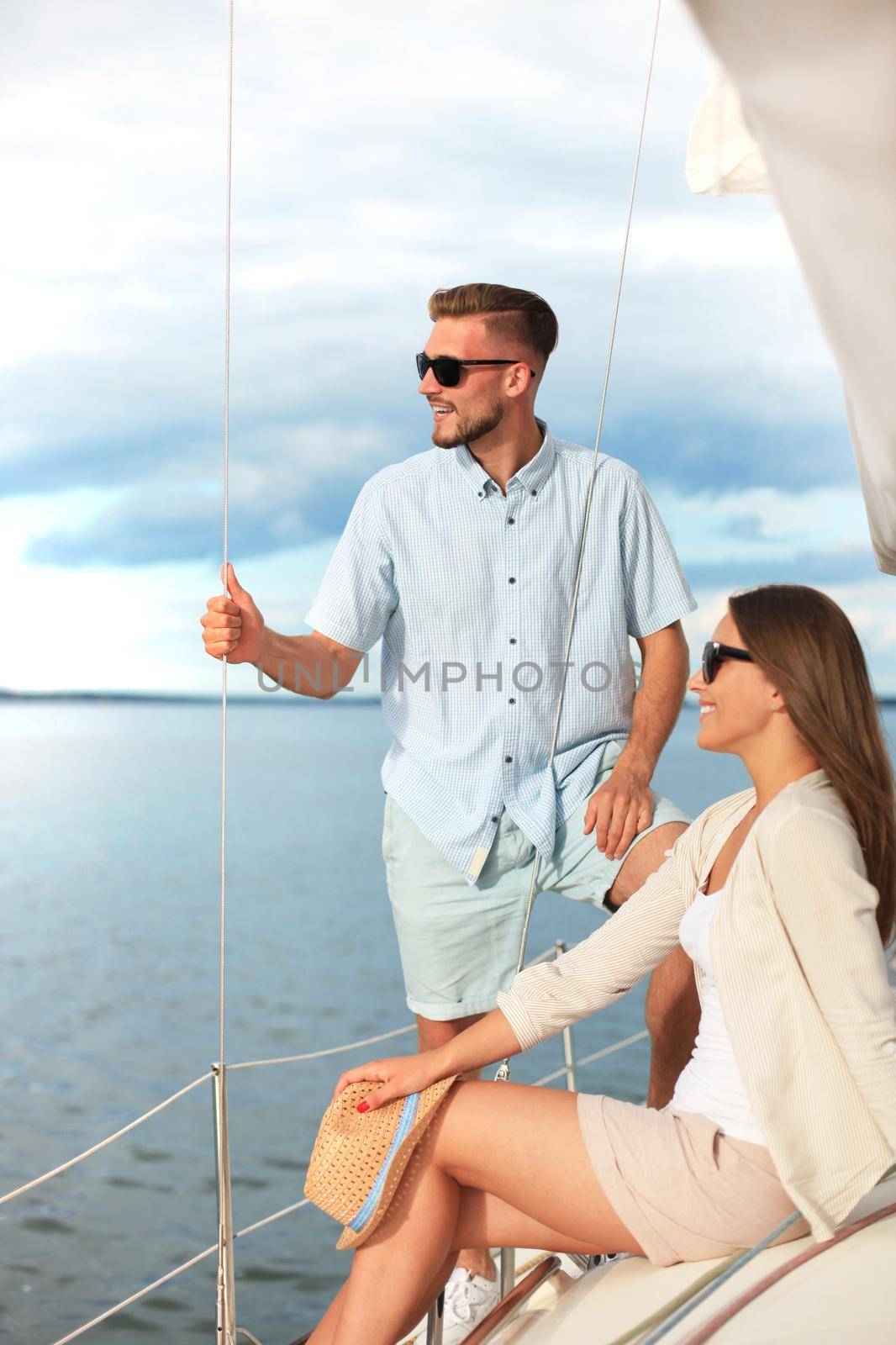 Attractive couple on a yacht enjoy bright sunny day on vacation. by tsyhun