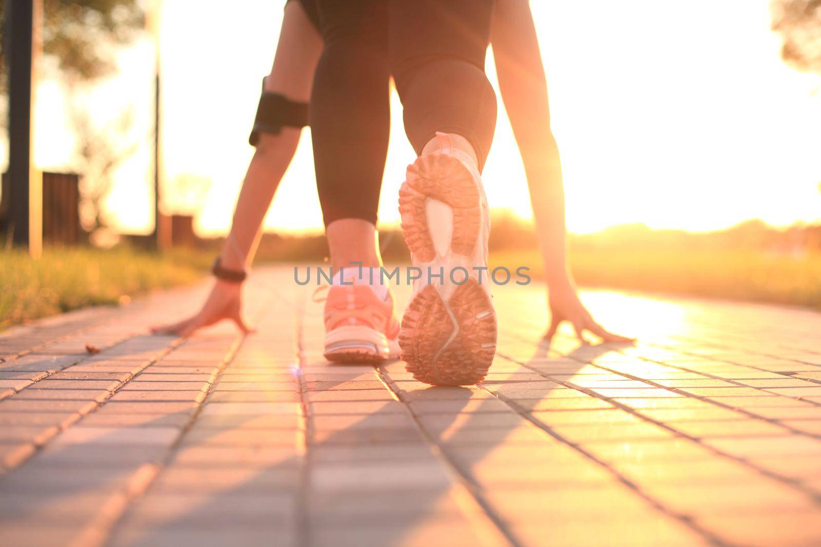 Runner feet running on road closeup on shoe, outdoor at sunset or sunrise in city by tsyhun
