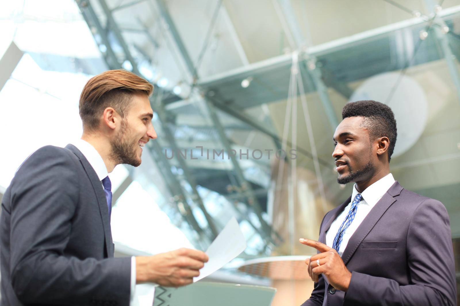 Two multinational young businessmen discussing business at meeting in office. by tsyhun