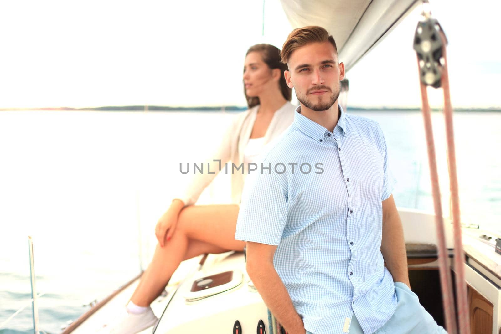 Attractive couple on a yacht enjoy bright sunny day on vacation.