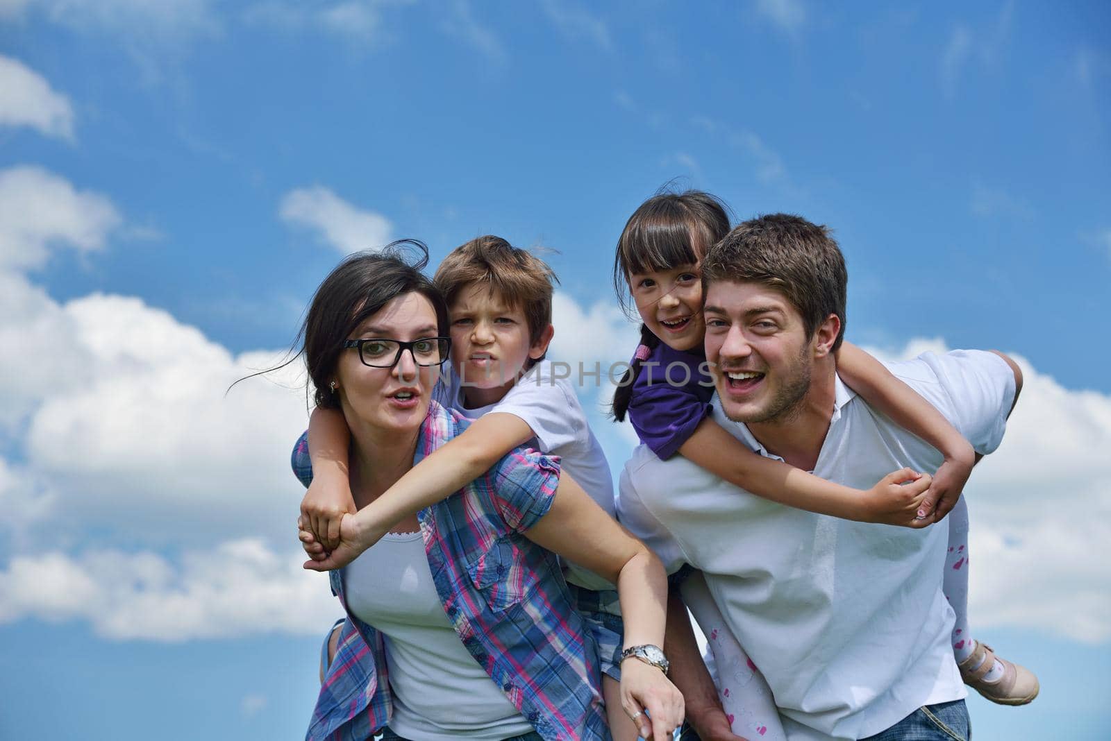 happy young family with their kids have fun and relax outdoors in nature with blue sky in background