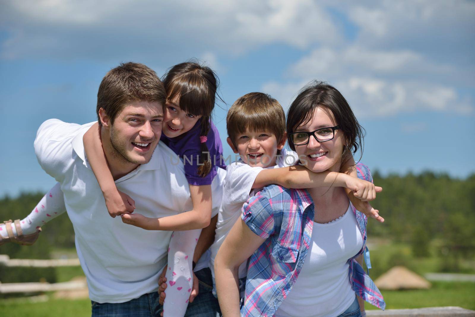 happy young family with their kids have fun and relax outdoors in nature with blue sky in background