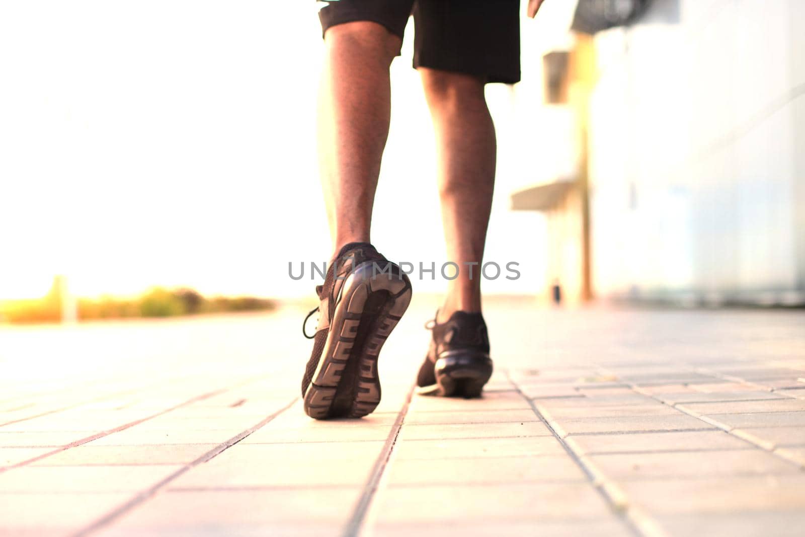 African man legs running while exercising outdoors, at sunrise or sunset.