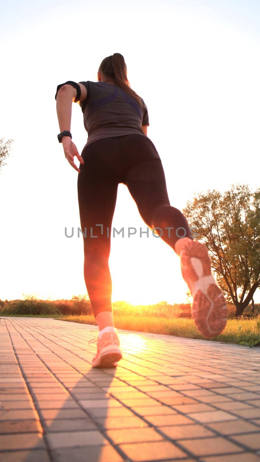 Young attractive sporty fitness woman running while exercising outdoors at sunset or sunrise by tsyhun