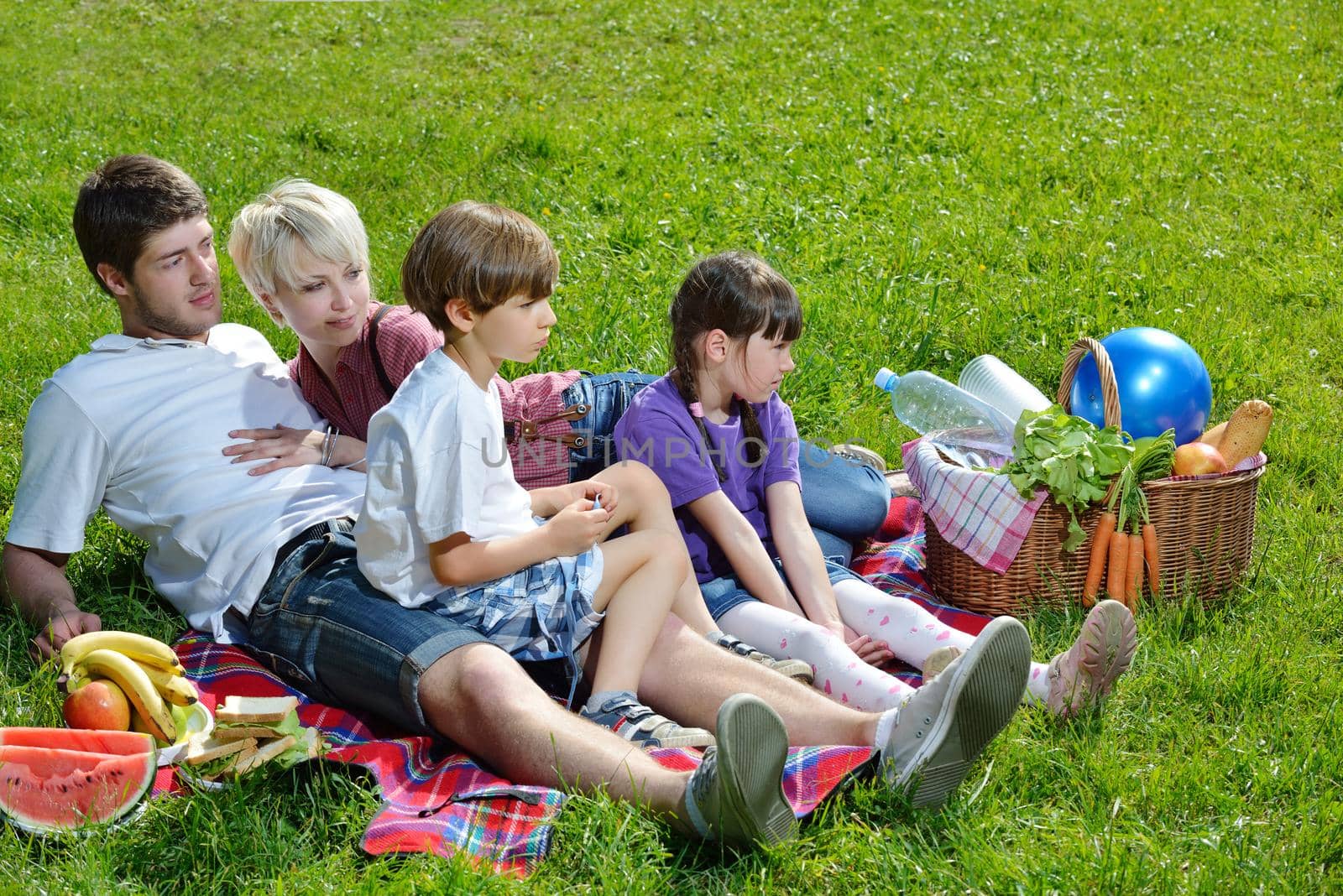 Happy young  family playing together with kids and eat healthy food  in a picnic outdoors