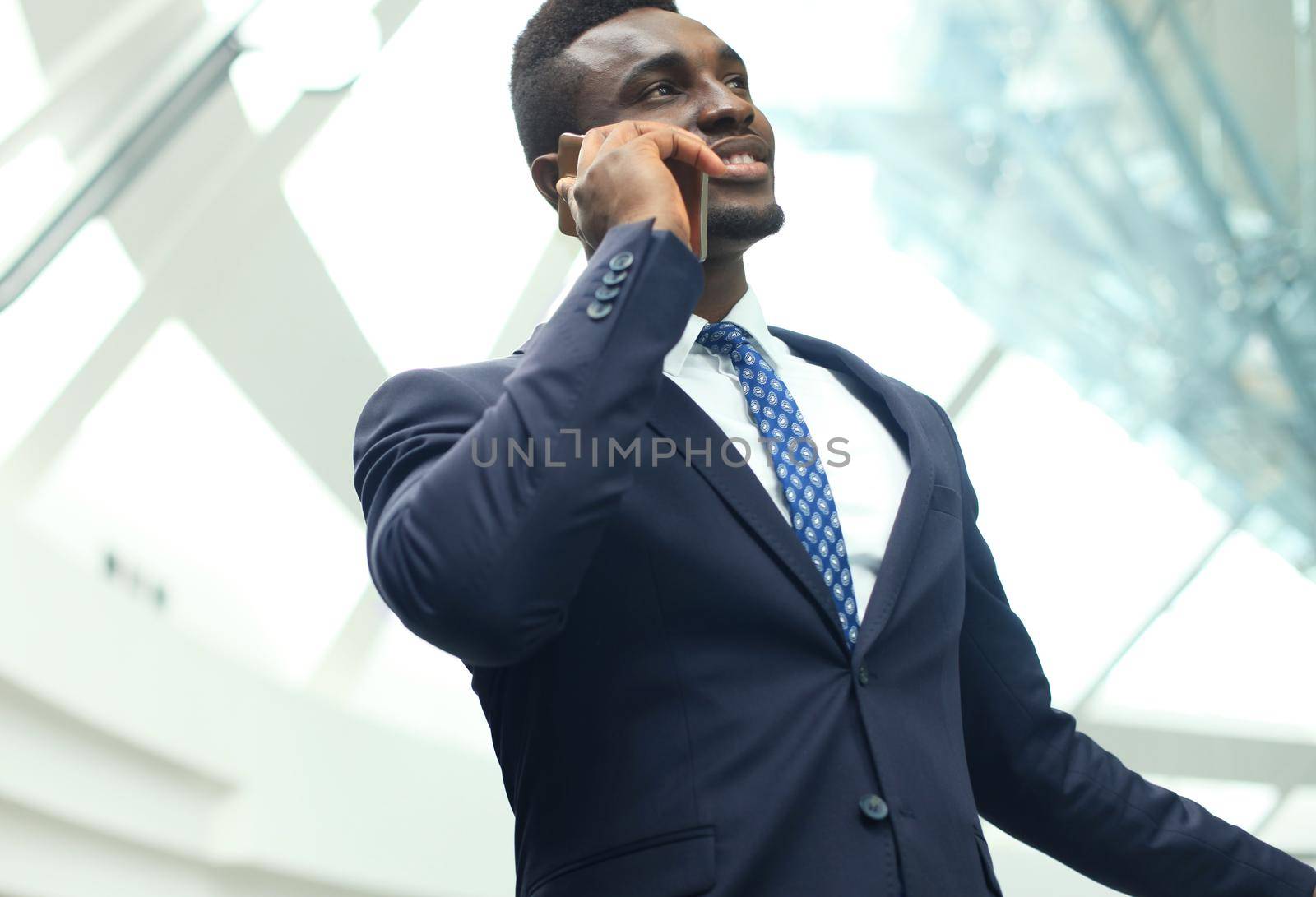 Successful handsome african american businessman talking on mobile phone in modern office. by tsyhun