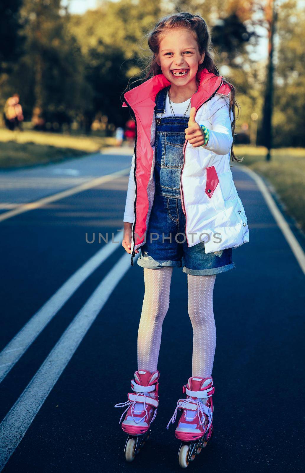 Happy little girl on roller skates on a sunny day on the roller track