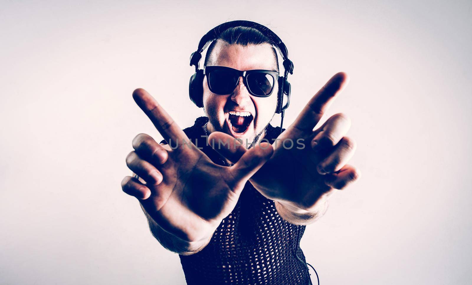 view from the top - DJ - rapper in a stylish t-shirt with headphones and with hands up on white background . the photo has a empty space for your text