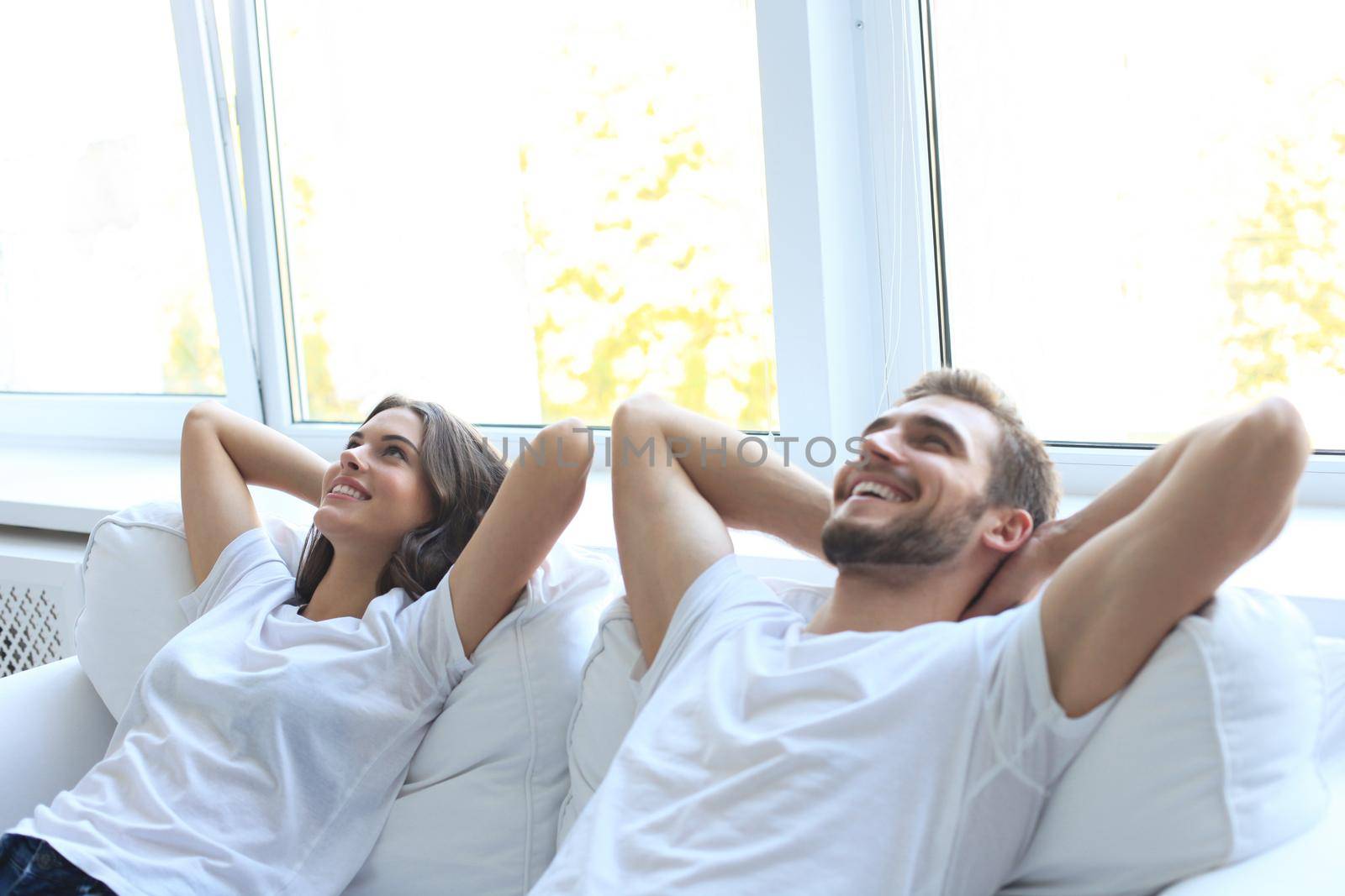 Smiling beautiful couple sitting on a sofa and dreaming about new home.