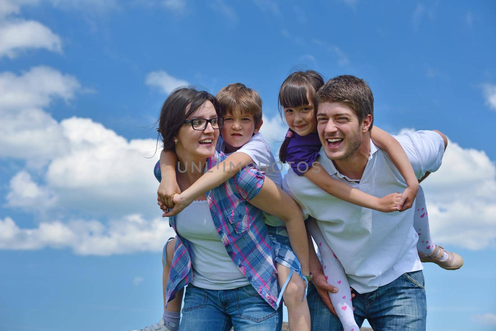 happy young family with their kids have fun and relax outdoors in nature with blue sky in background