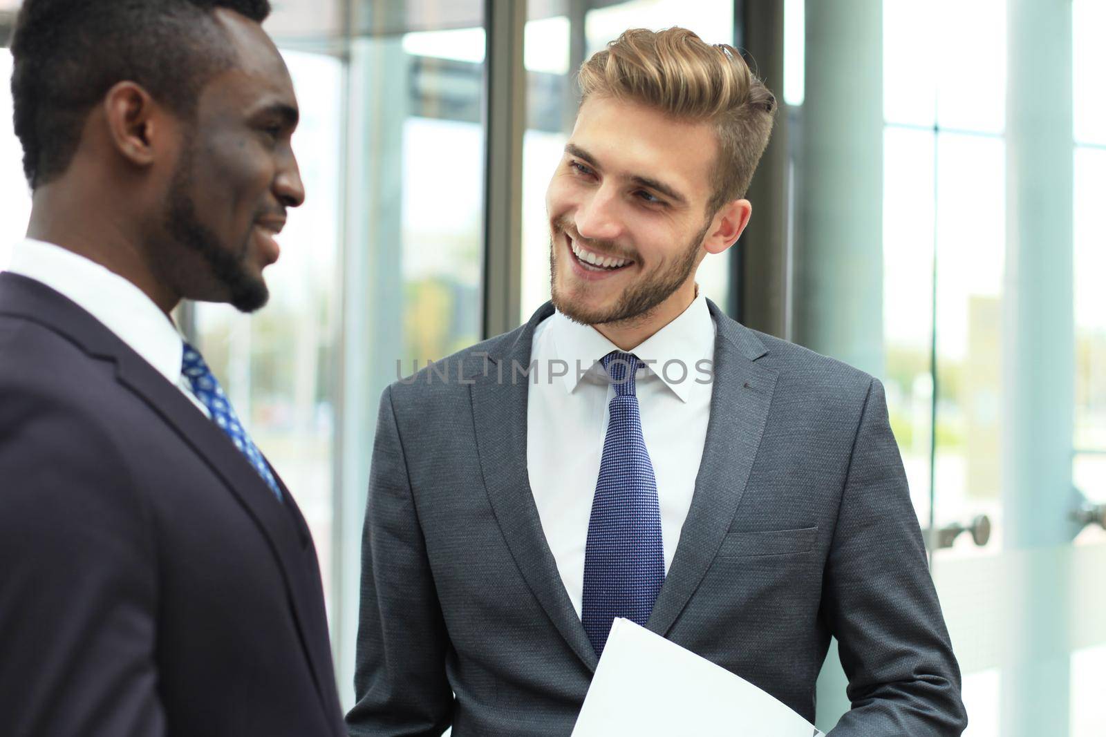 Two multinational young businessmen discussing business at meeting in office. by tsyhun