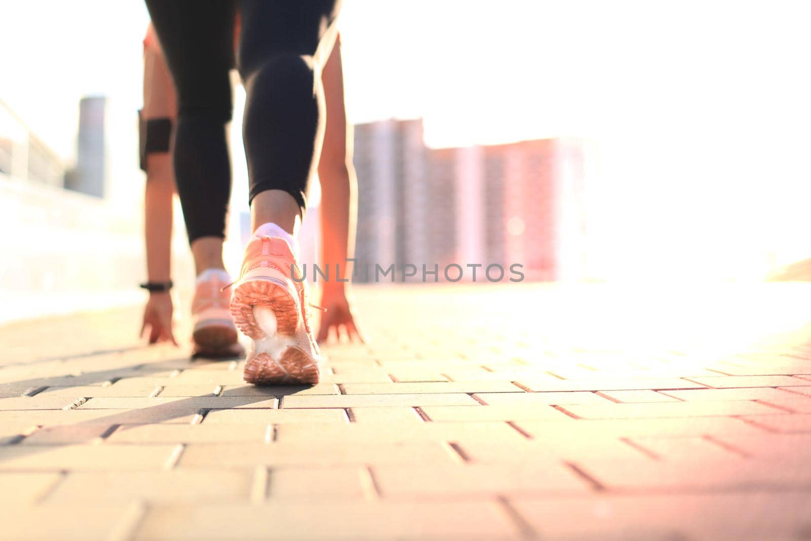 Young fitness attractive sporty girlrunner in start position outdoor at sunset or sunrise in city. by tsyhun