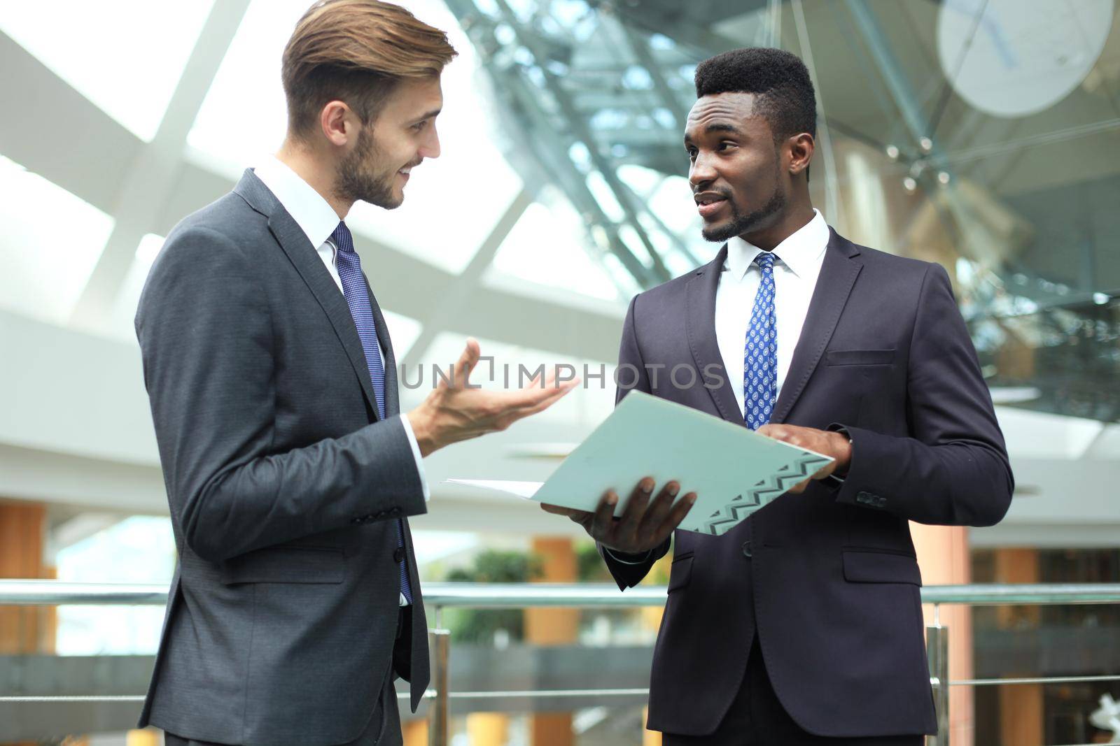 Two multinational young businessmen discussing business at meeting in office.