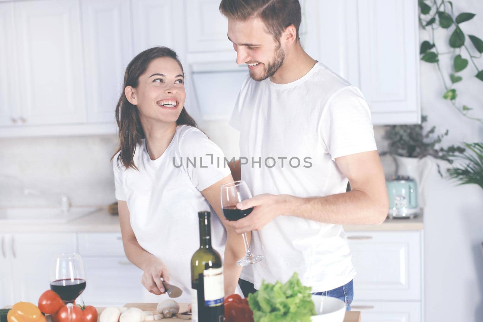 Beautiful young couple preparing a healthy meal together while spending free time at home. by tsyhun