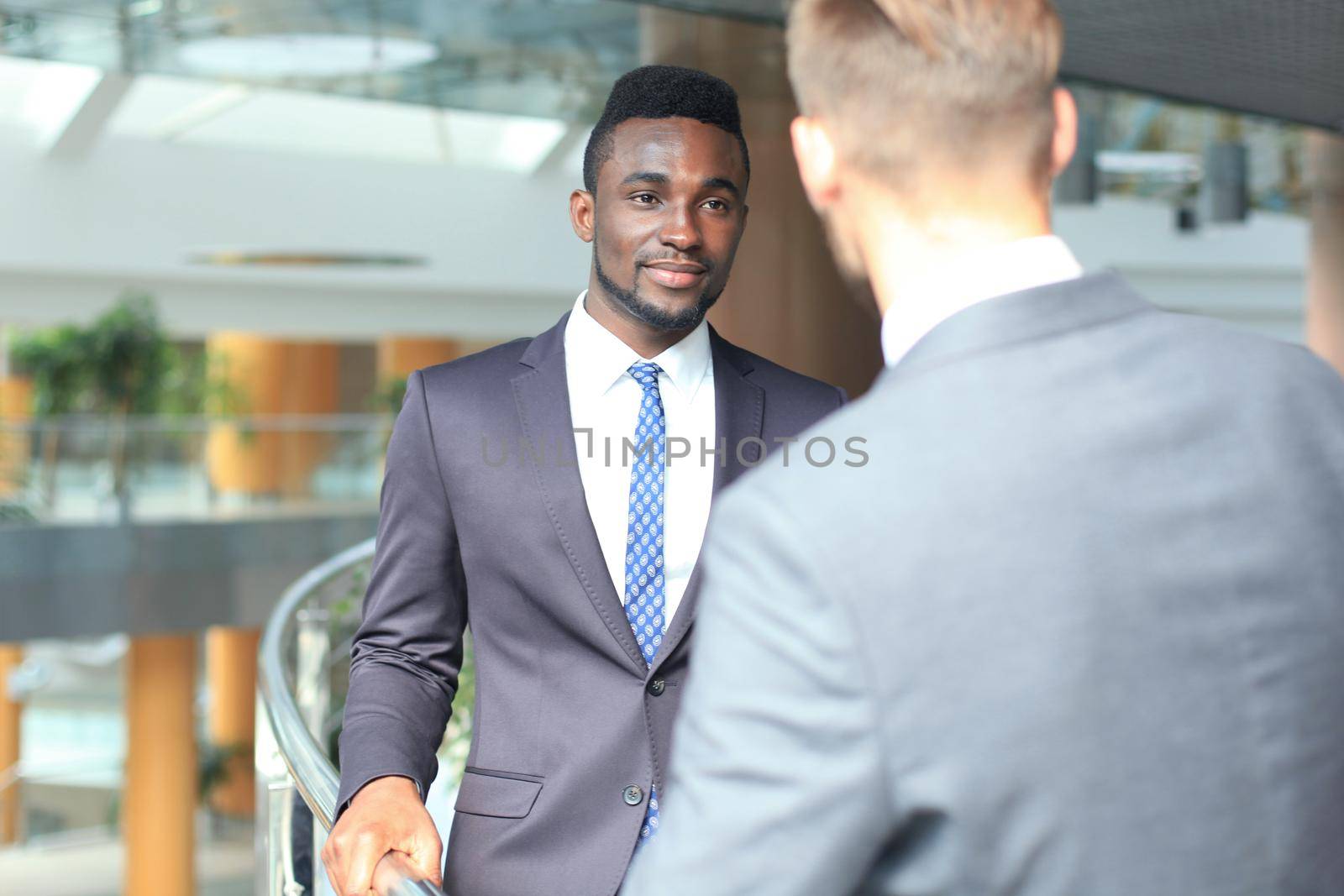 Two multinational young businessmen discussing business at meeting in office. by tsyhun