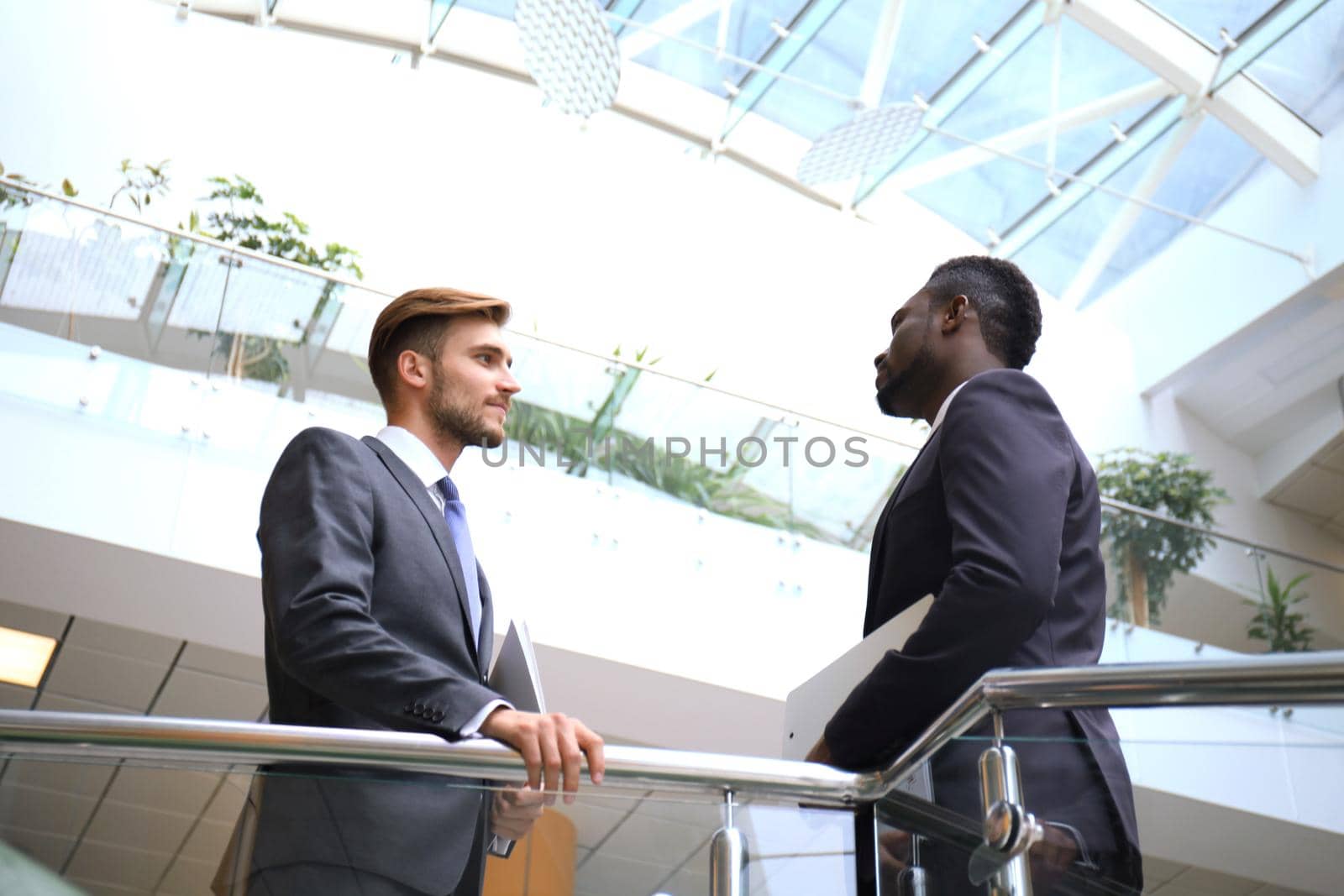 Bottom view. Two multinational young businessmen discussing at office during business meeting.