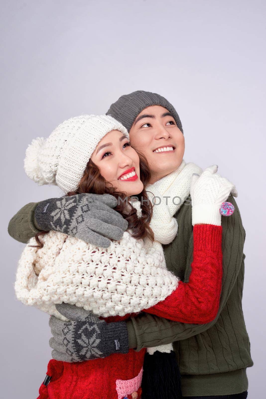 Happy young lovers in knitted woolen clothing hugging and looking together.