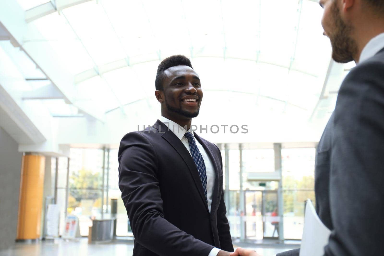 Business meeting. African American businessman shaking hands with caucasian businessman. by tsyhun