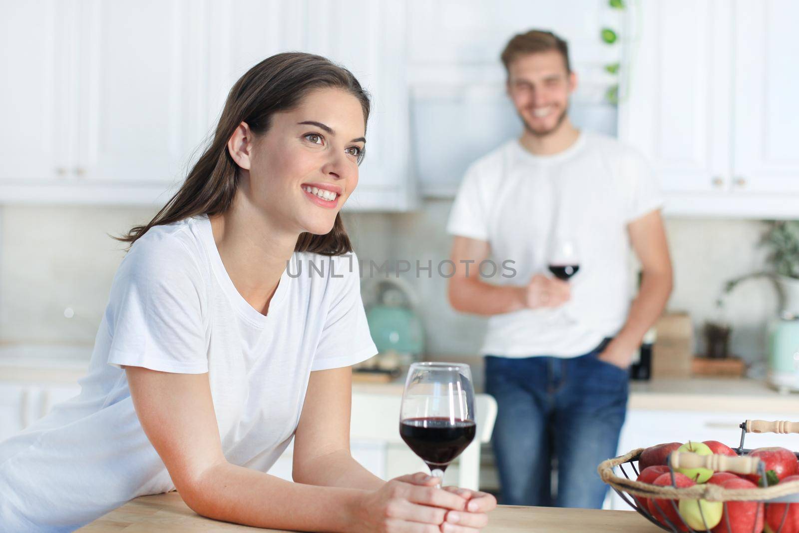 Pretty young woman drinking some wine at home in kitchen.