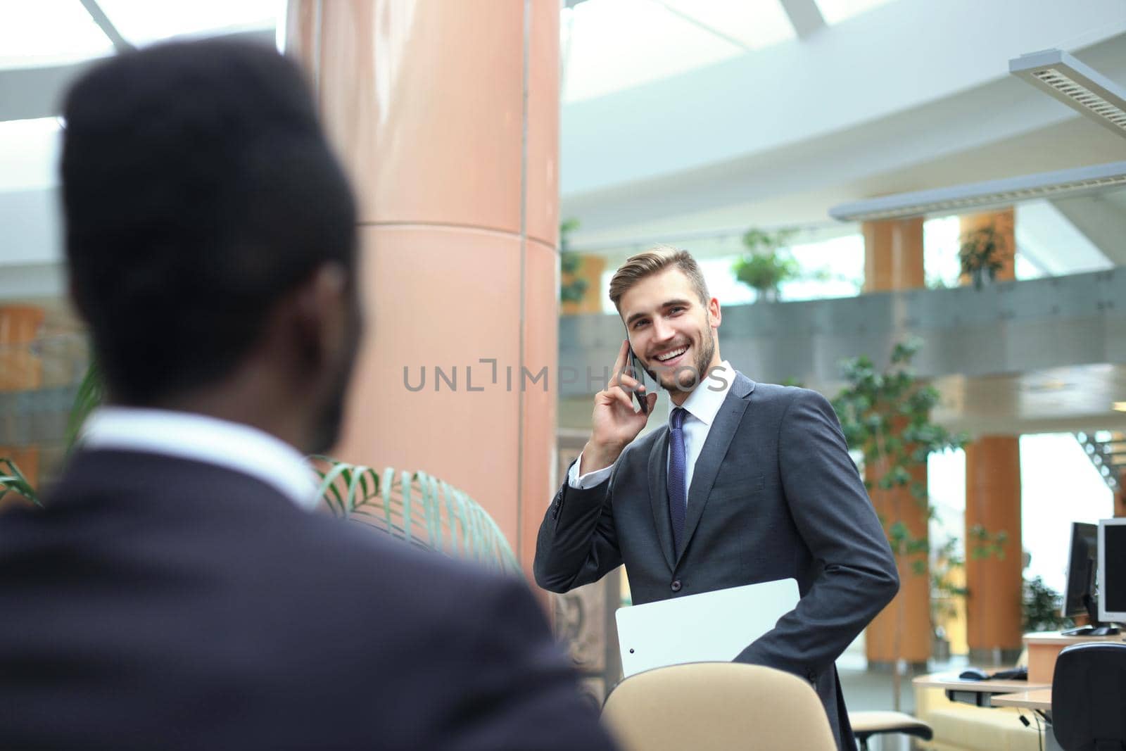 two multinational young businessmen in suit communicating on the mobile phone.