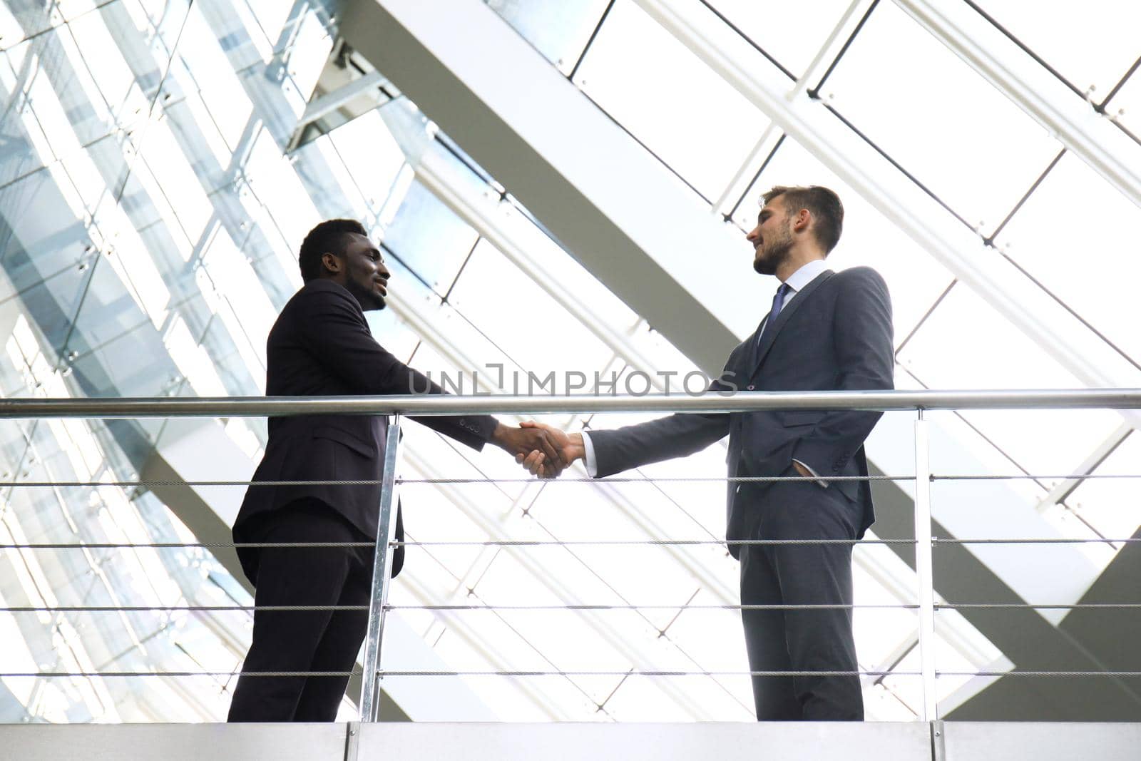 Business meeting. African American businessman shaking hands with caucasian businessman. by tsyhun