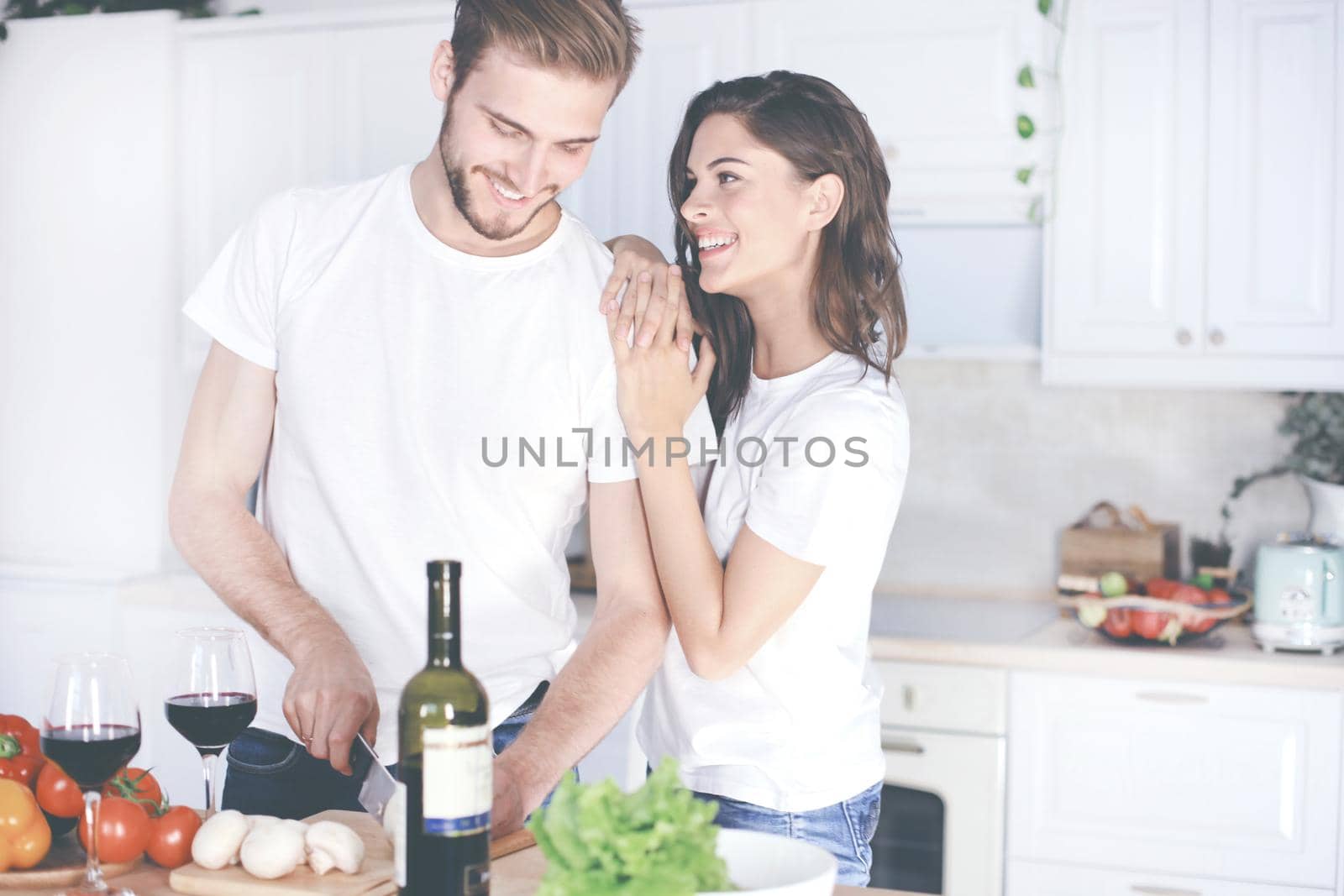 Beautiful young couple preparing a healthy meal together while spending free time at home. by tsyhun