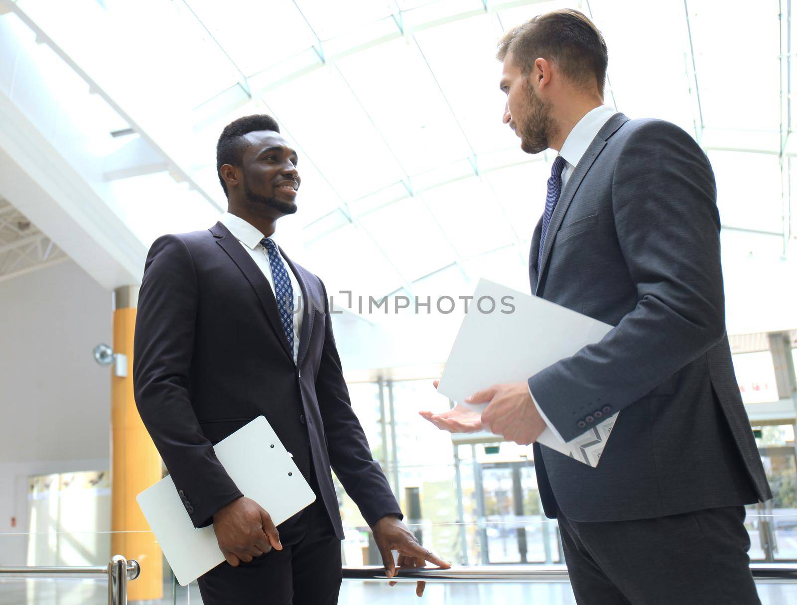 Two multinational young businessmen discussing business at meeting in office.