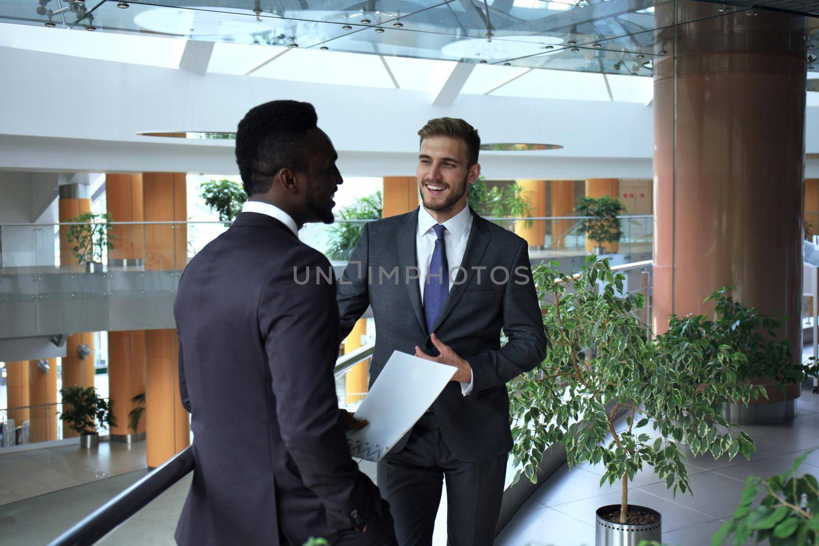 Two multinational young businessmen discussing business at meeting in office.