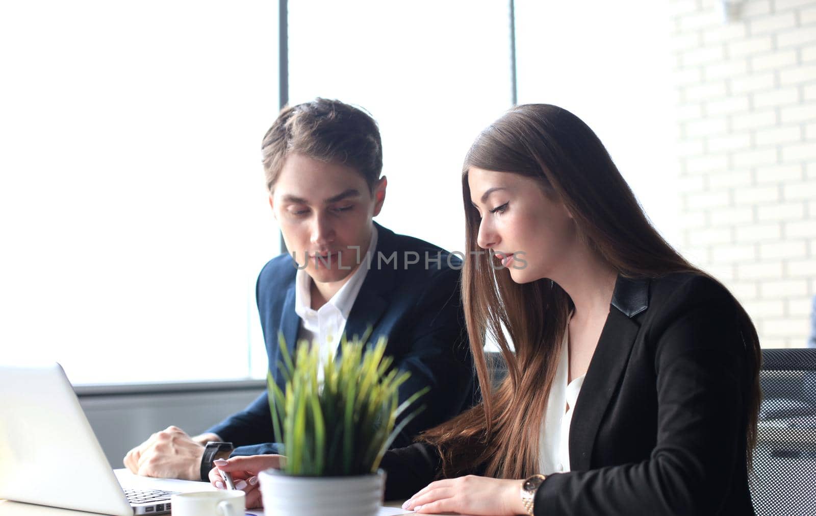 Business partners working together at office desk, they are using a laptop.